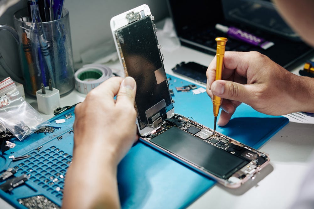 Rick fixing a Smart Phone, using a precision screwdriver beside small tools and parts.
